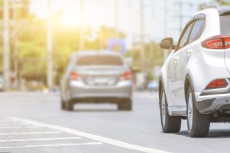 Auto jazdí po mokrej jarnej ceste s výtlkmi.