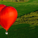 Ilustračný záber na farebný teplovzdušný balón počas prípravy na let alebo počas letu nad krajinou.